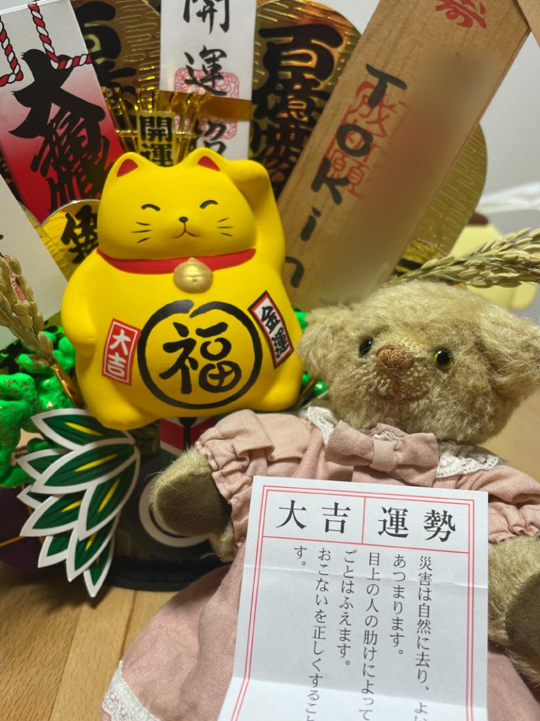 熊手に乗った黄色い招き猫。「大吉」のおみくじを持って座るクマのぬいぐるみ