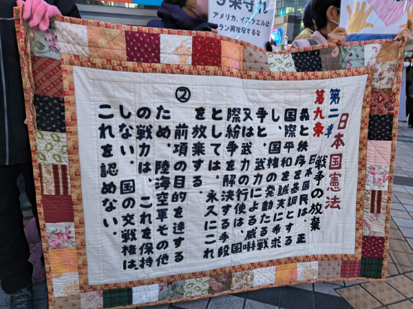 大きいパッチワーク作品。日本国憲法9条の文章が縫われている。第九条　日本国民は、正義と秩序を基調とする国際平和を誠実に希求し、国権の発動たる戦争と、武力による威嚇又は武力の行使は、国際紛争を解決する手段としては、永久にこれを放棄する。
②　前項の目的を達するため、陸海空軍その他の戦力は、これを保持しない。国の交戦権は、これを認めない