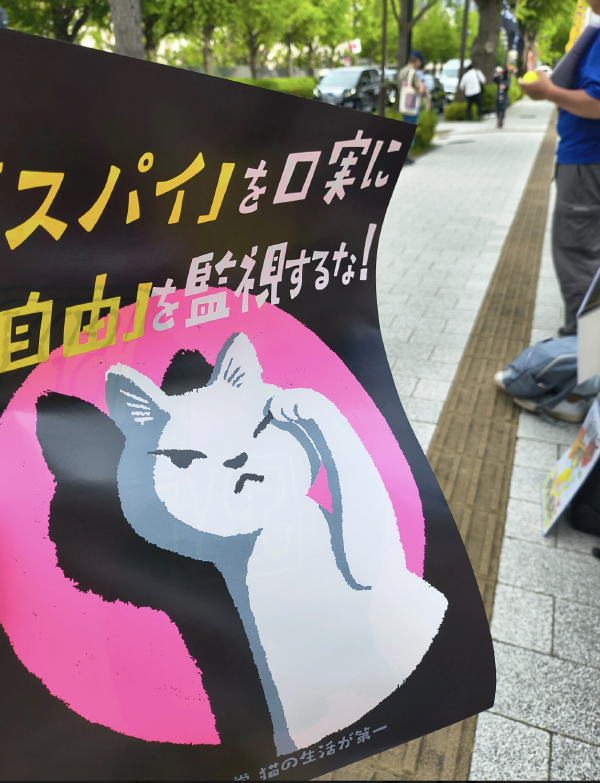 「スパイを口実に 自由を監視するな」と描かれた、ねこのイラストのポスター