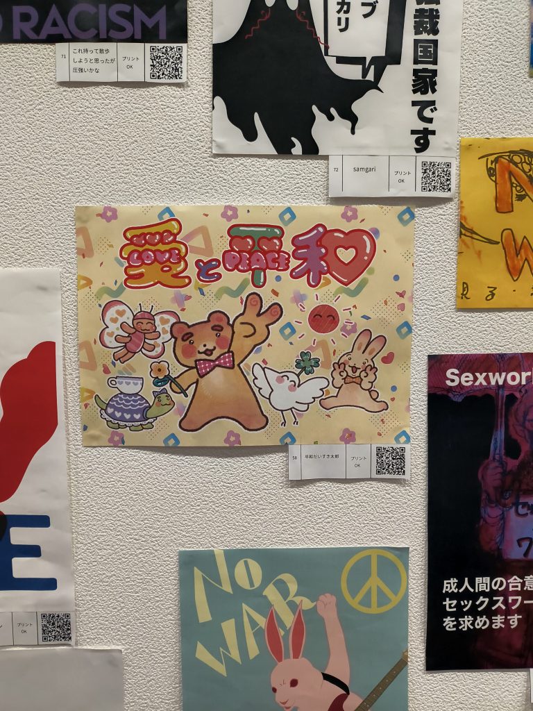 たくさんのプラカードが貼られた壁面。中央に「愛と平和」の文字と共にうさぎやクマが踊っているイラスト。