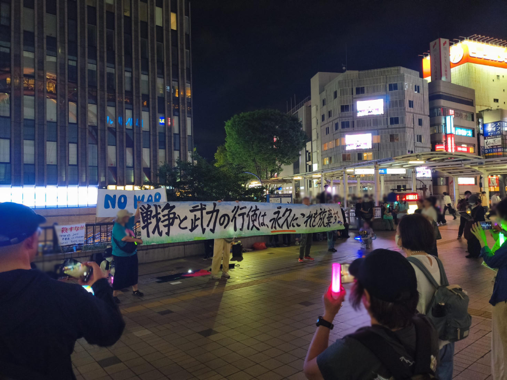 立川駅前の写真。「no war」「戦争と武力の行使は永久にこれを放棄する」と書かれた横断幕が掲げられている。